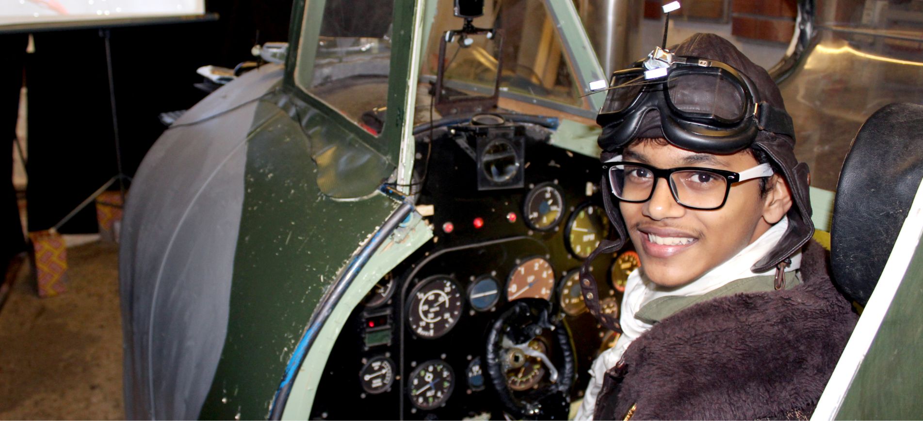 A young student at Brockwood Park School inside a mockup airplane