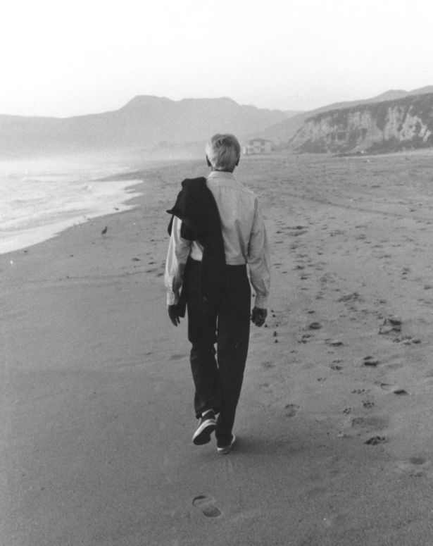 Krishnamurti seen from behind walking on a beach