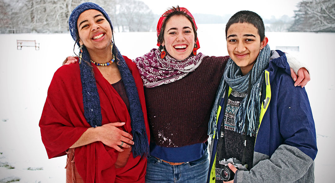 Three Brockwood Park School students smiling in the snow