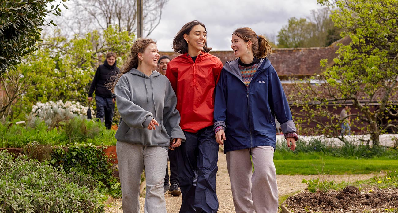 Three Brockwood Park School students smiling in the snow